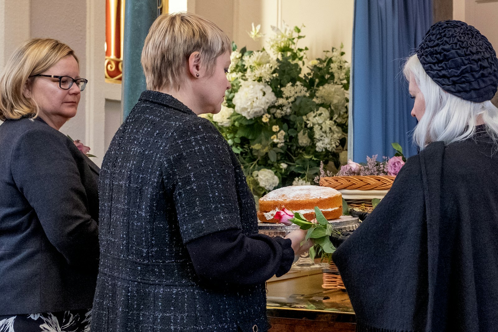 a group of people standing around a table with a cake on it