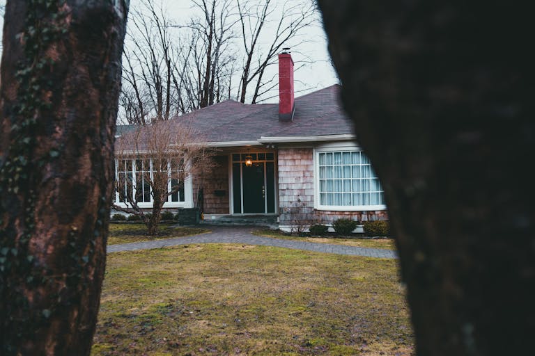 Exterior of suburban shabby brick house with large windows chimney and street lamp over entrance doorway and yard