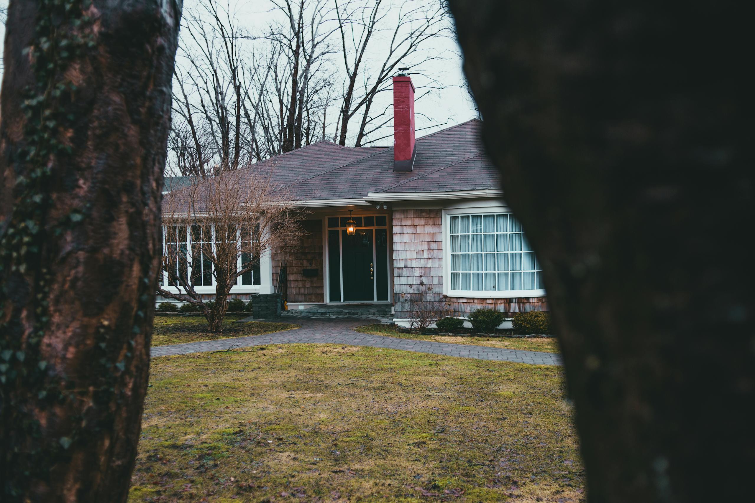 Exterior of suburban shabby brick house with large windows chimney and street lamp over entrance doorway and yard