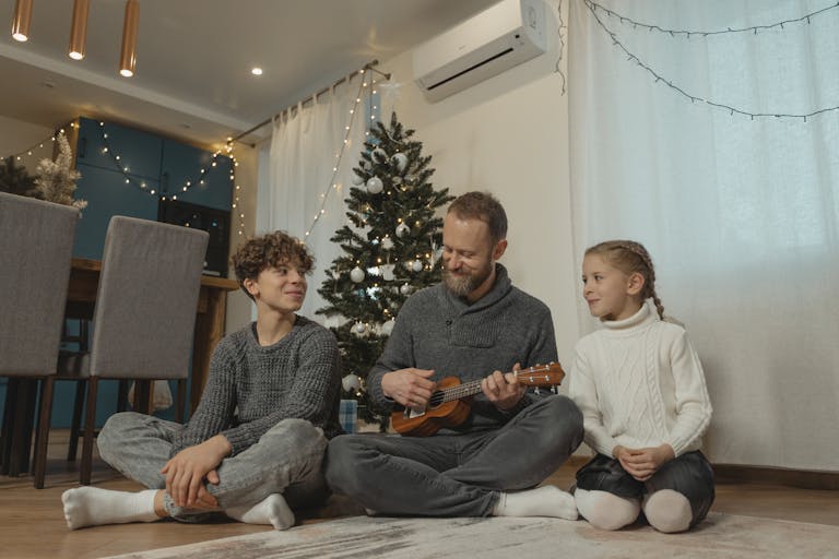 Father and children enjoying Christmas together with a ukulele in a warm home.
