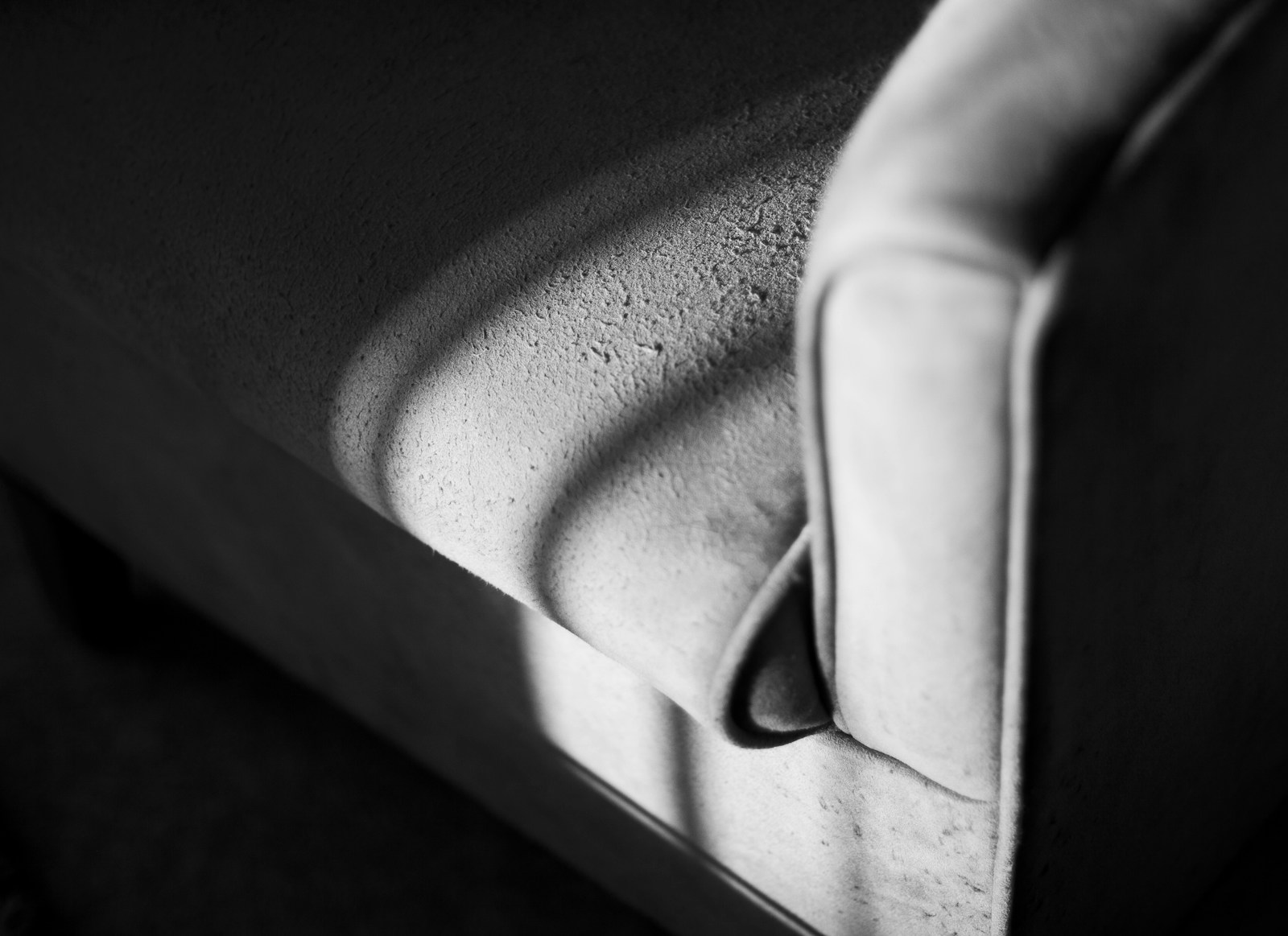 Close-up of a textured armchair with dramatic light and shadow.
