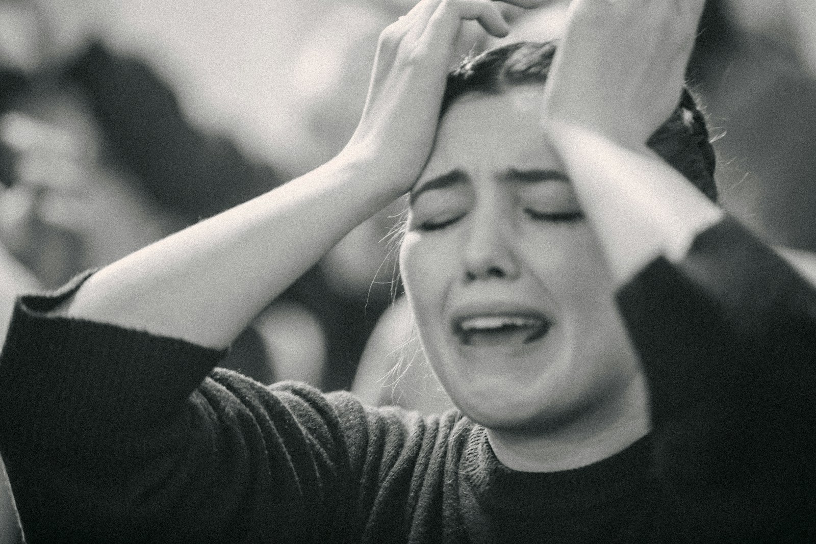 A black and white photo of a woman covering her eyes
