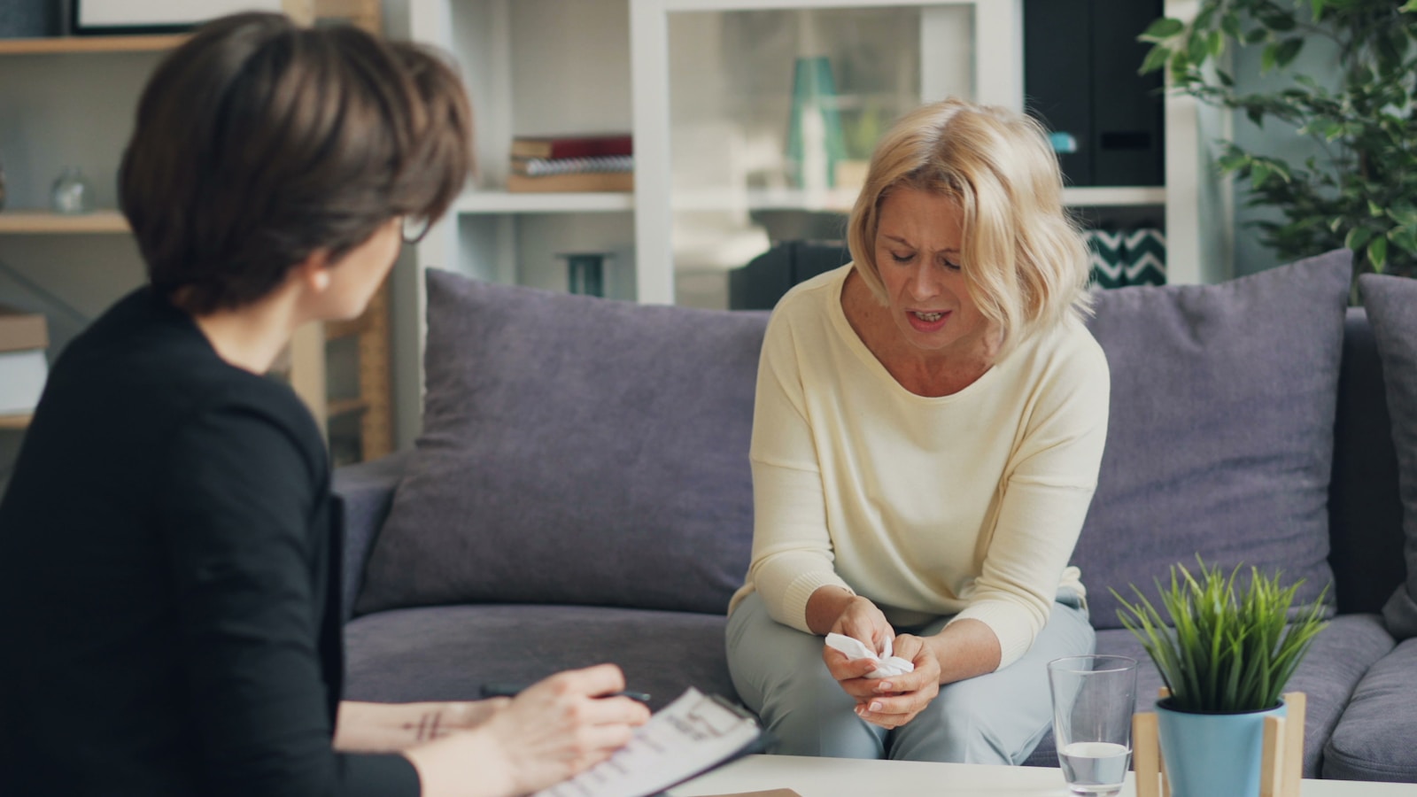 a woman sitting on a couch talking to another woman