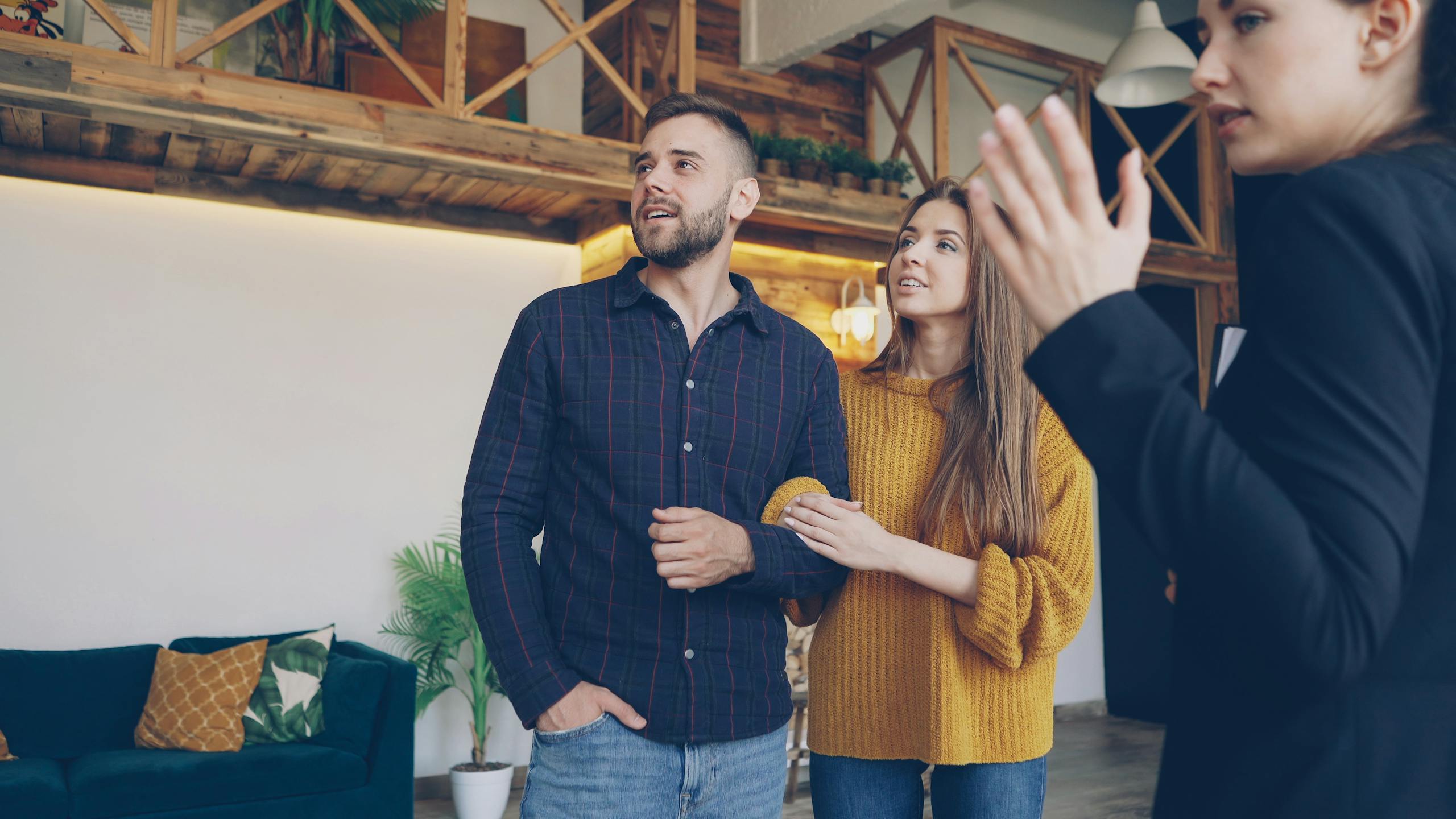 Happy couple exploring a stylish home with a real estate agent indoors.