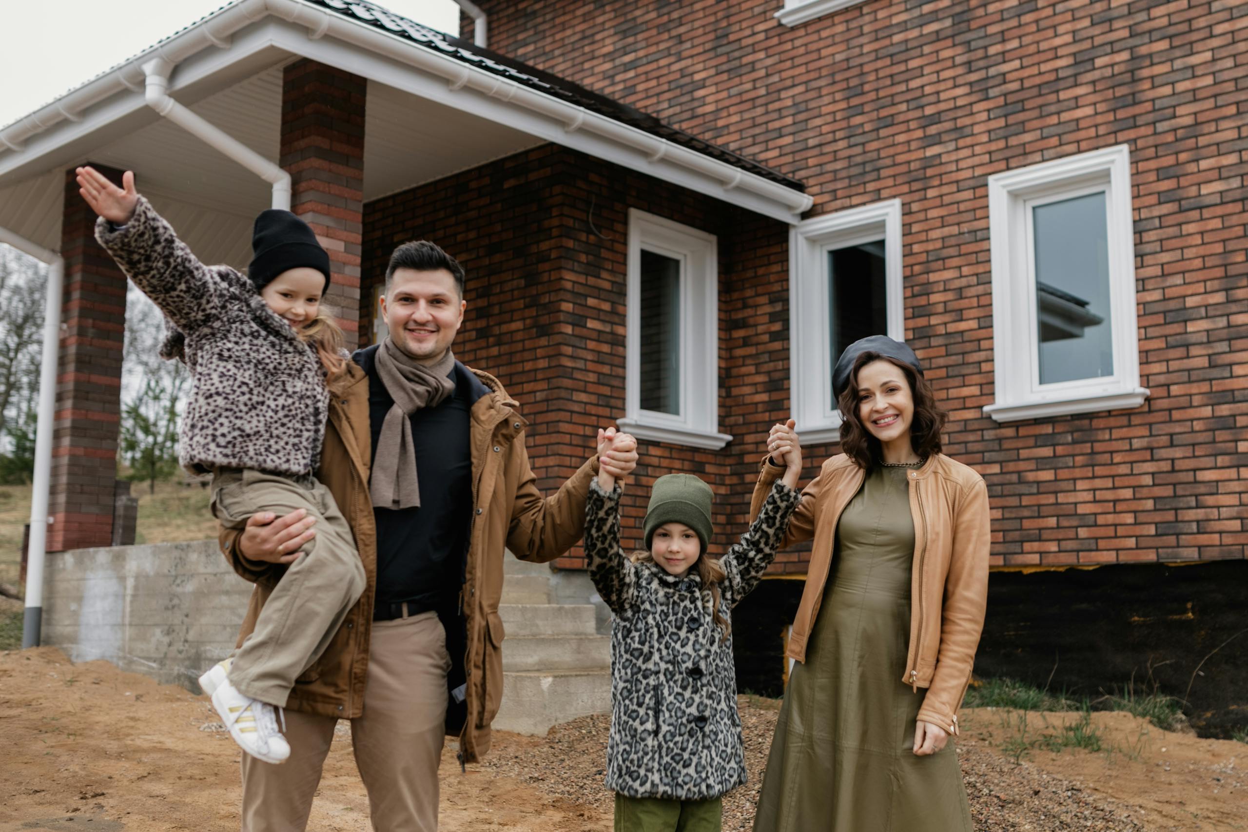 Joyful family celebrates new home purchase with smiles and warm attire.