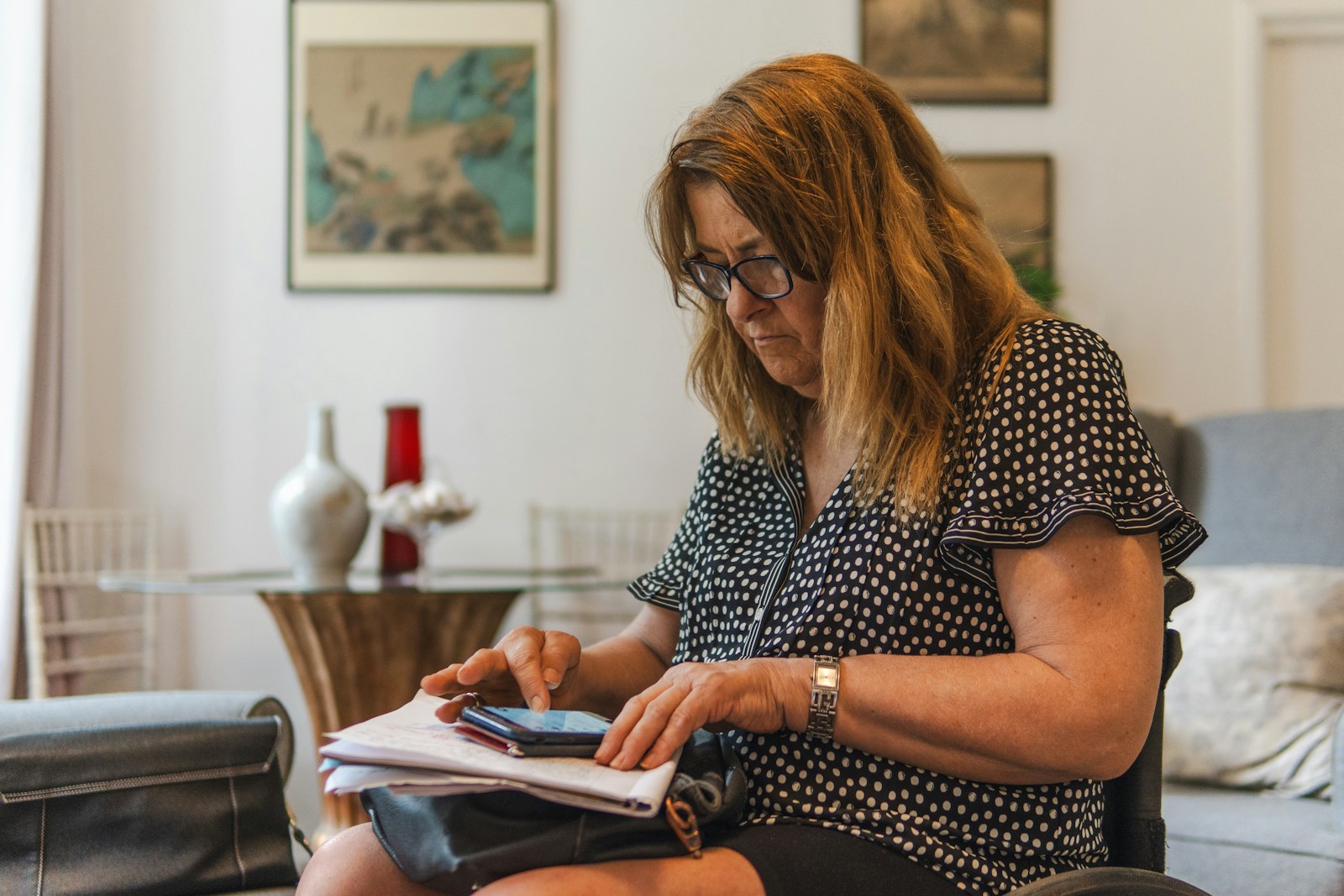 Woman looking at phone while writing on paper