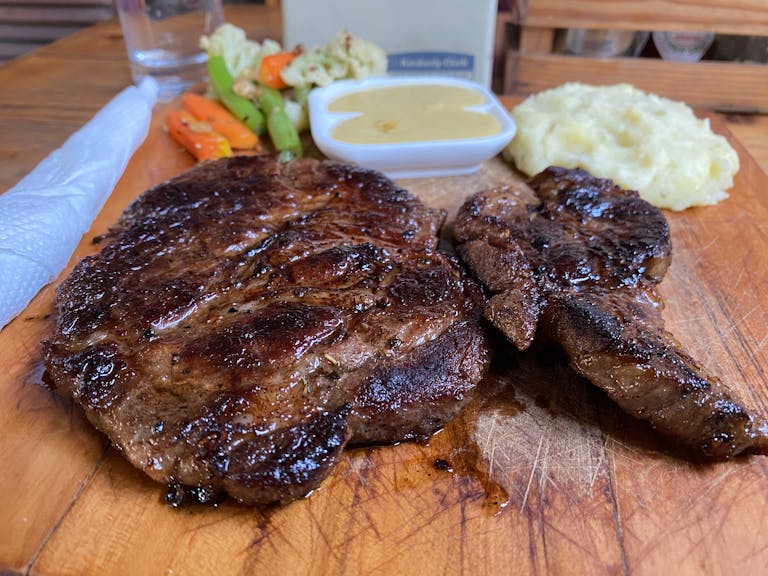 Juicy grilled steak served with creamy mashed potatoes and a side of sautéed vegetables.