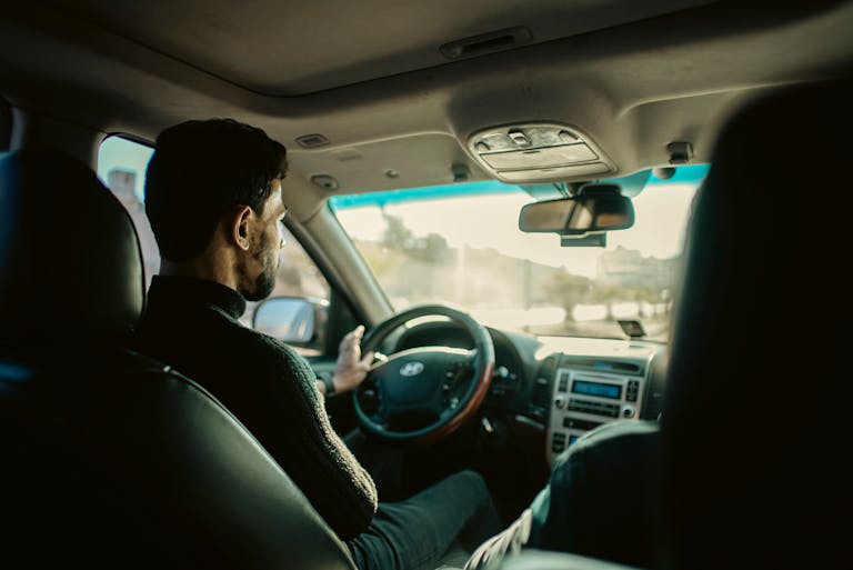 Man driving through city streets of Manbij, Aleppo, in a modern sedan.