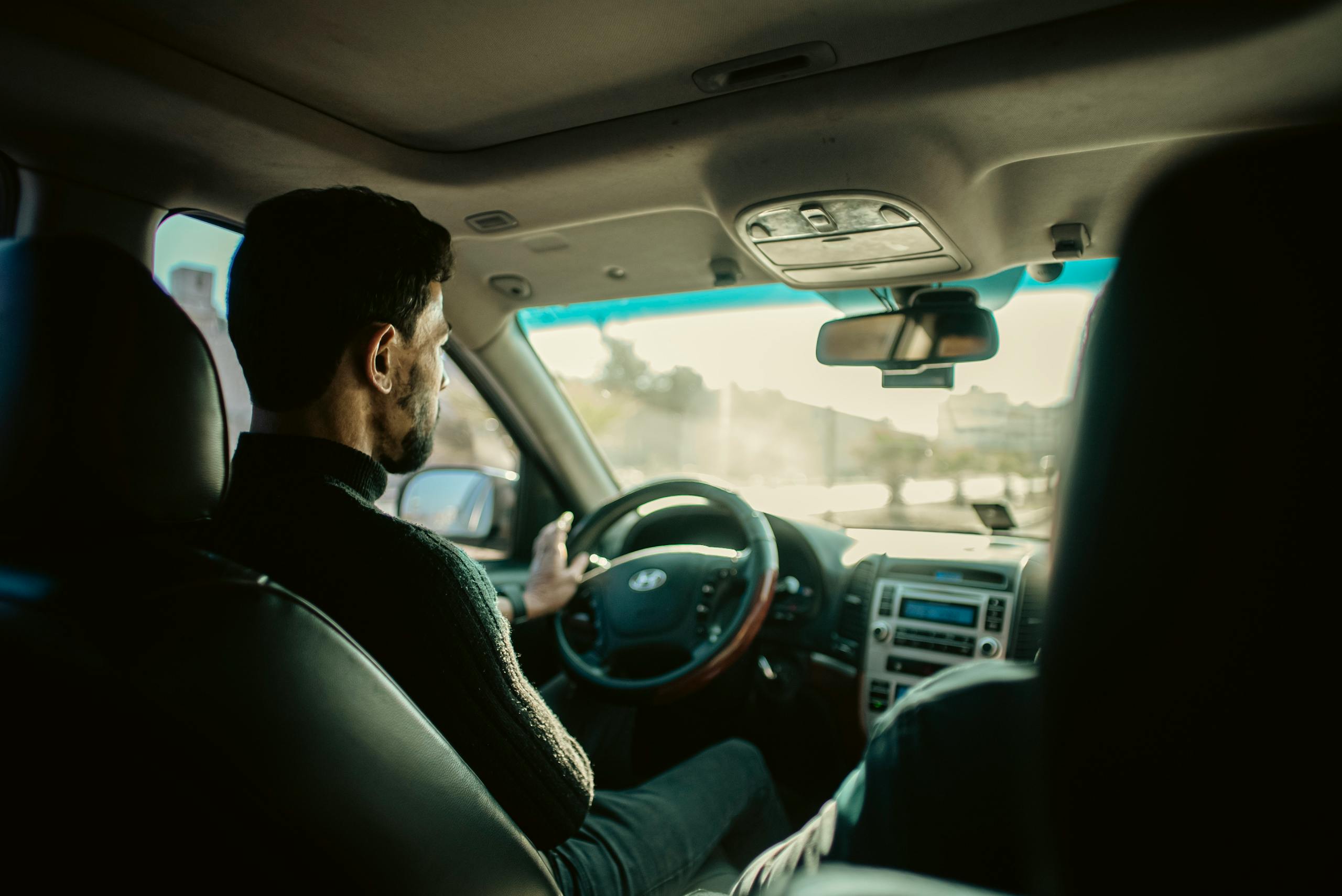 Man driving through city streets of Manbij, Aleppo, in a modern sedan.