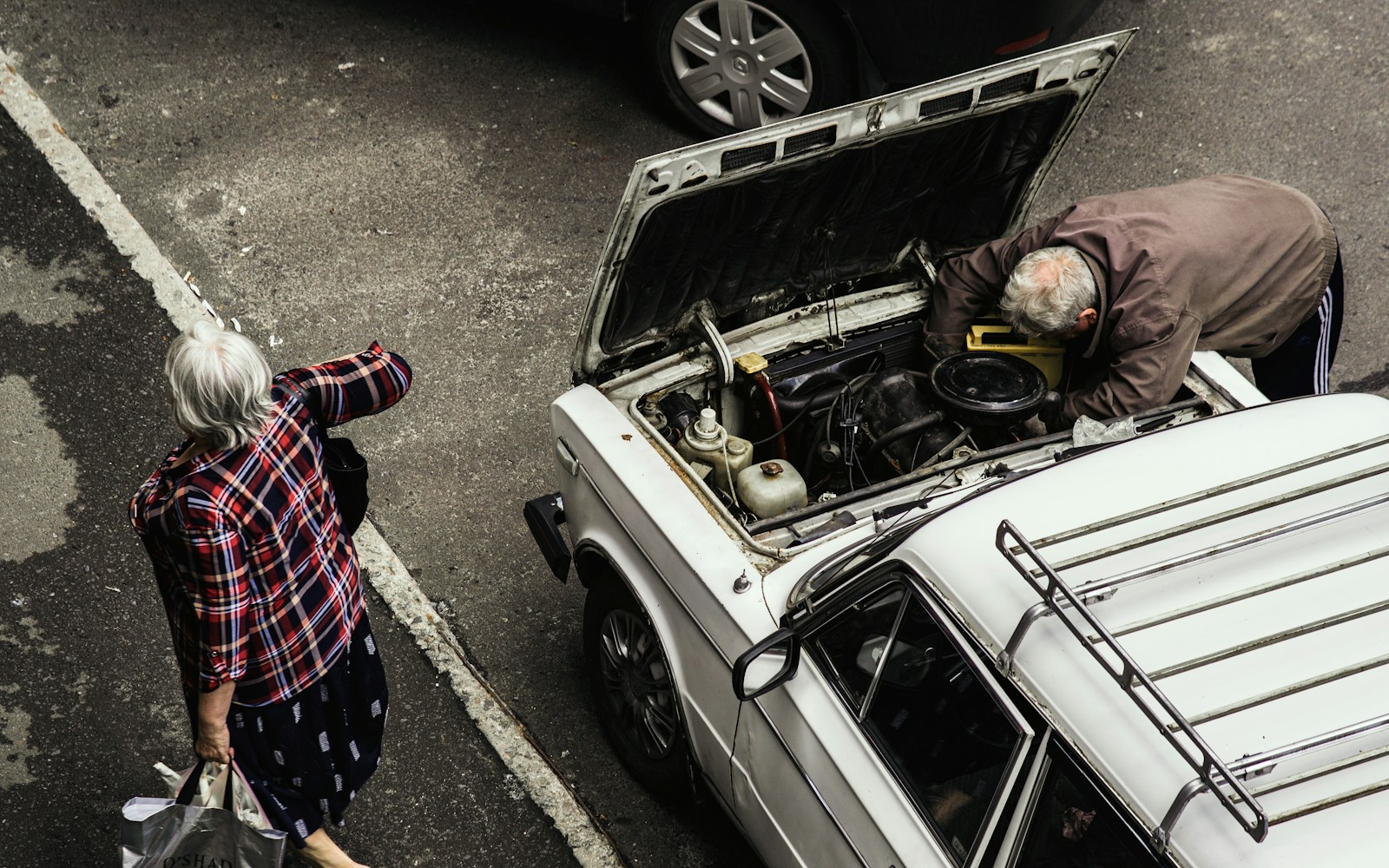 a man and a woman looking at a car with its hood open