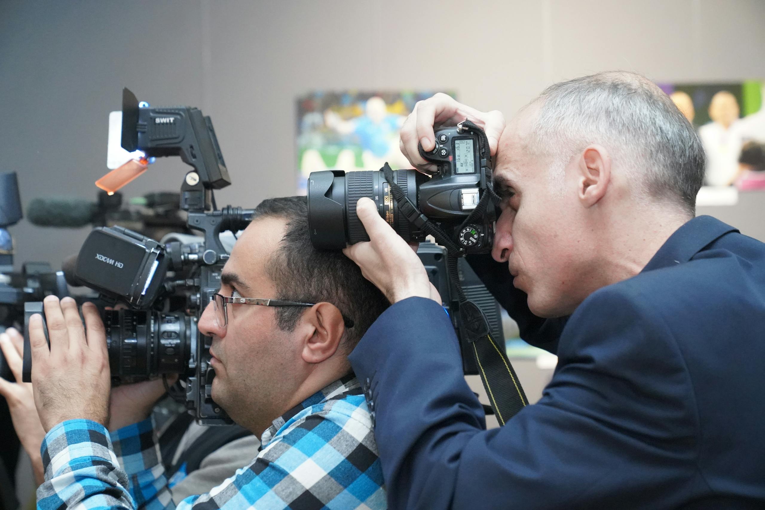 Photographers focusing on event coverage with advanced cameras indoors, showcasing media professionals in action.