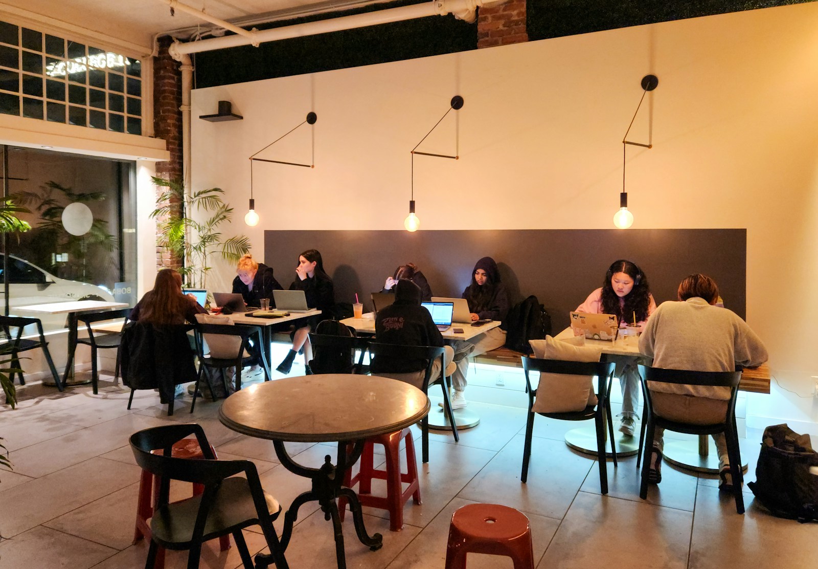 People work on laptops in a cozy coffee shop.