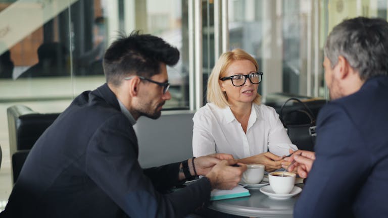 Professional team discussing ideas over coffee in a modern café setting.