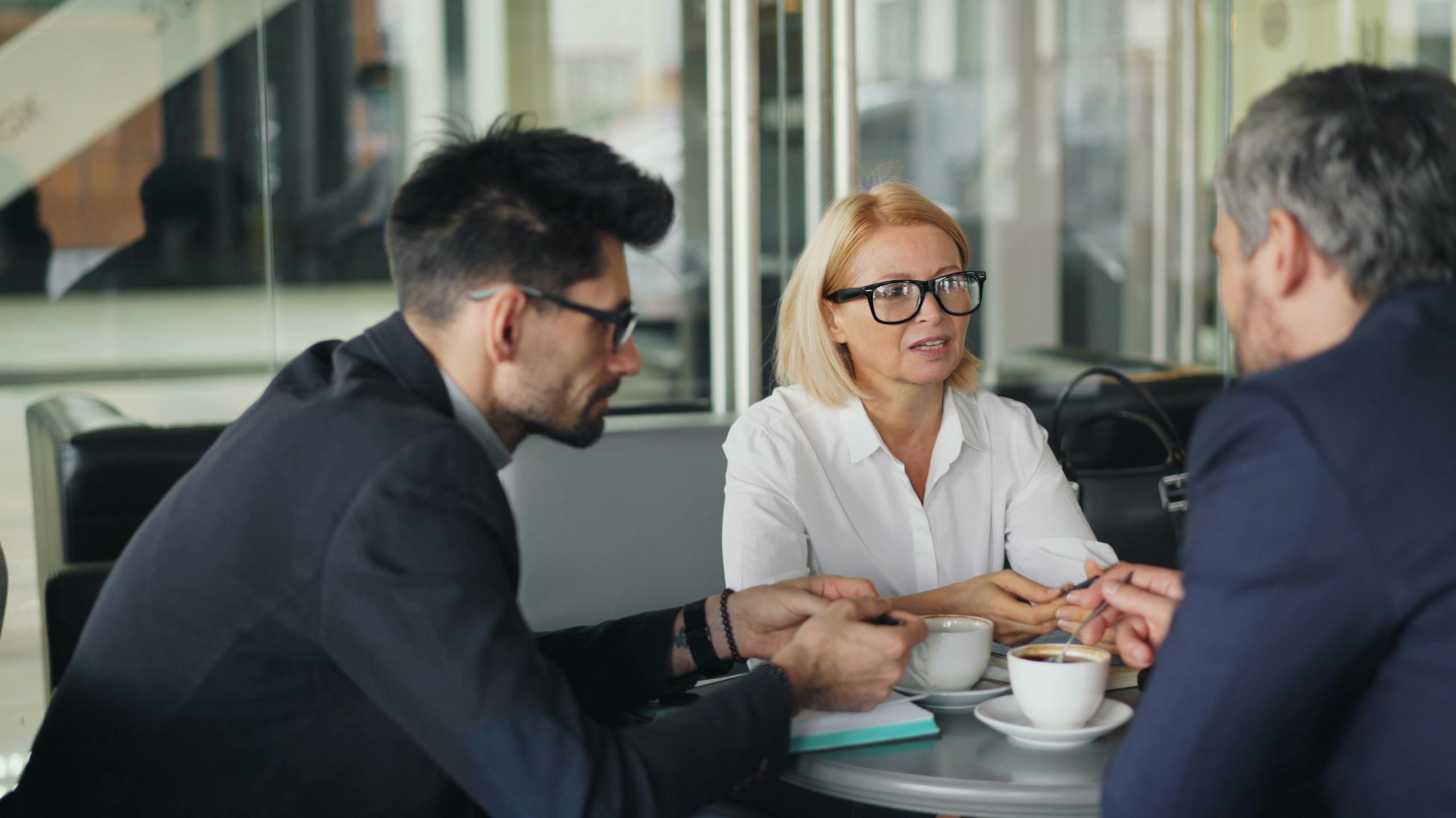 Professional team discussing ideas over coffee in a modern café setting.