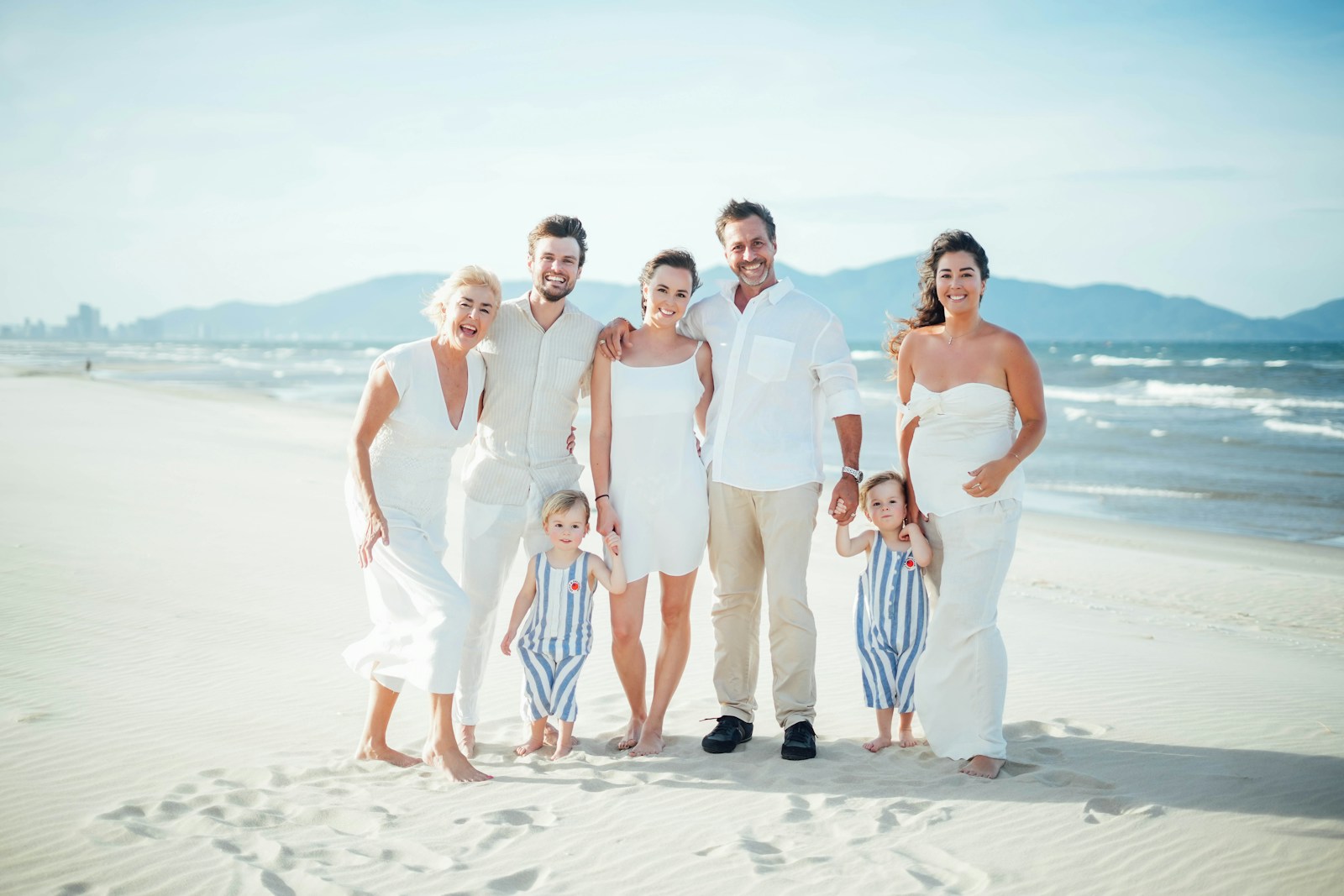A family poses for a photo on a sunny beach.