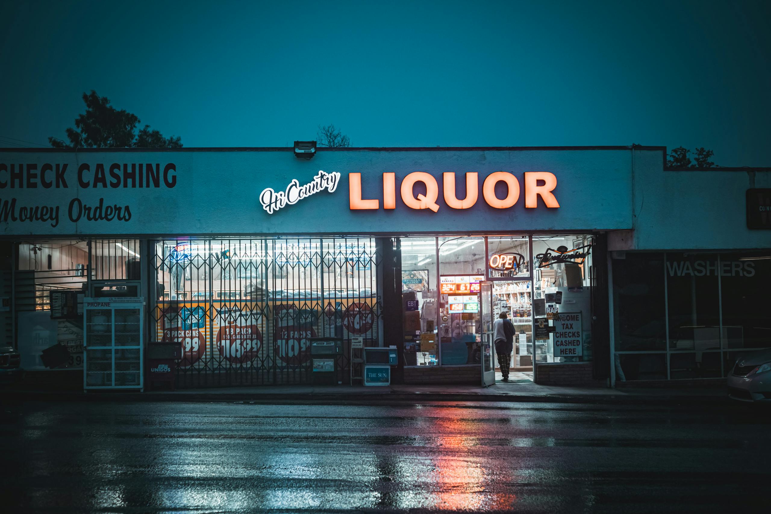 Rainy evening view of a neon-lit liquor store in Yucaipa, CA, United States.