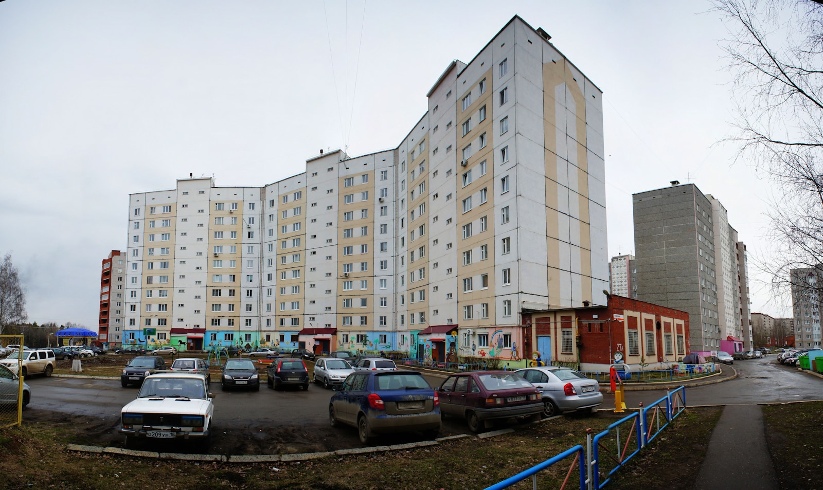 Apartment buildings with cars parked in front.