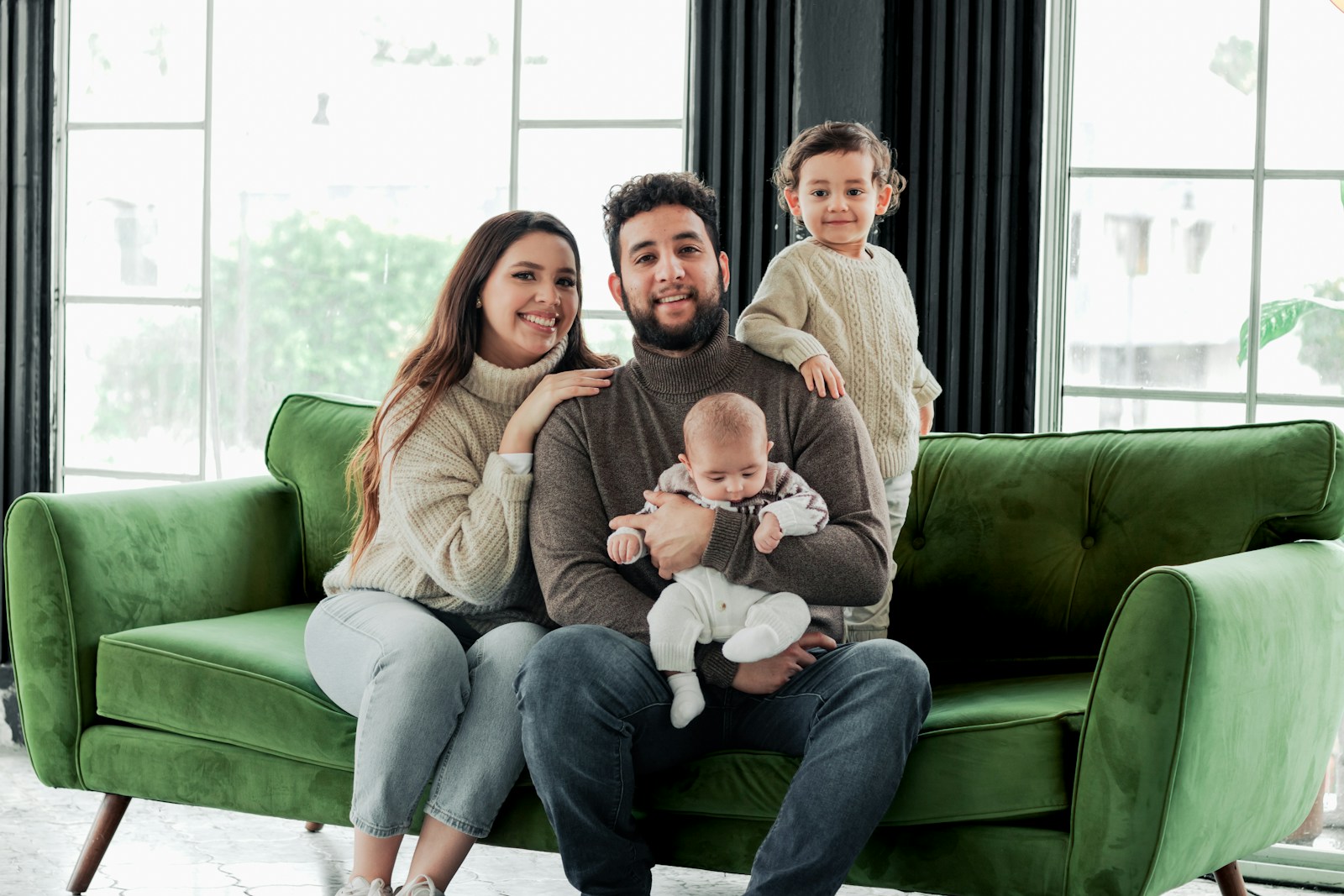 a family sitting on a green couch in a living room