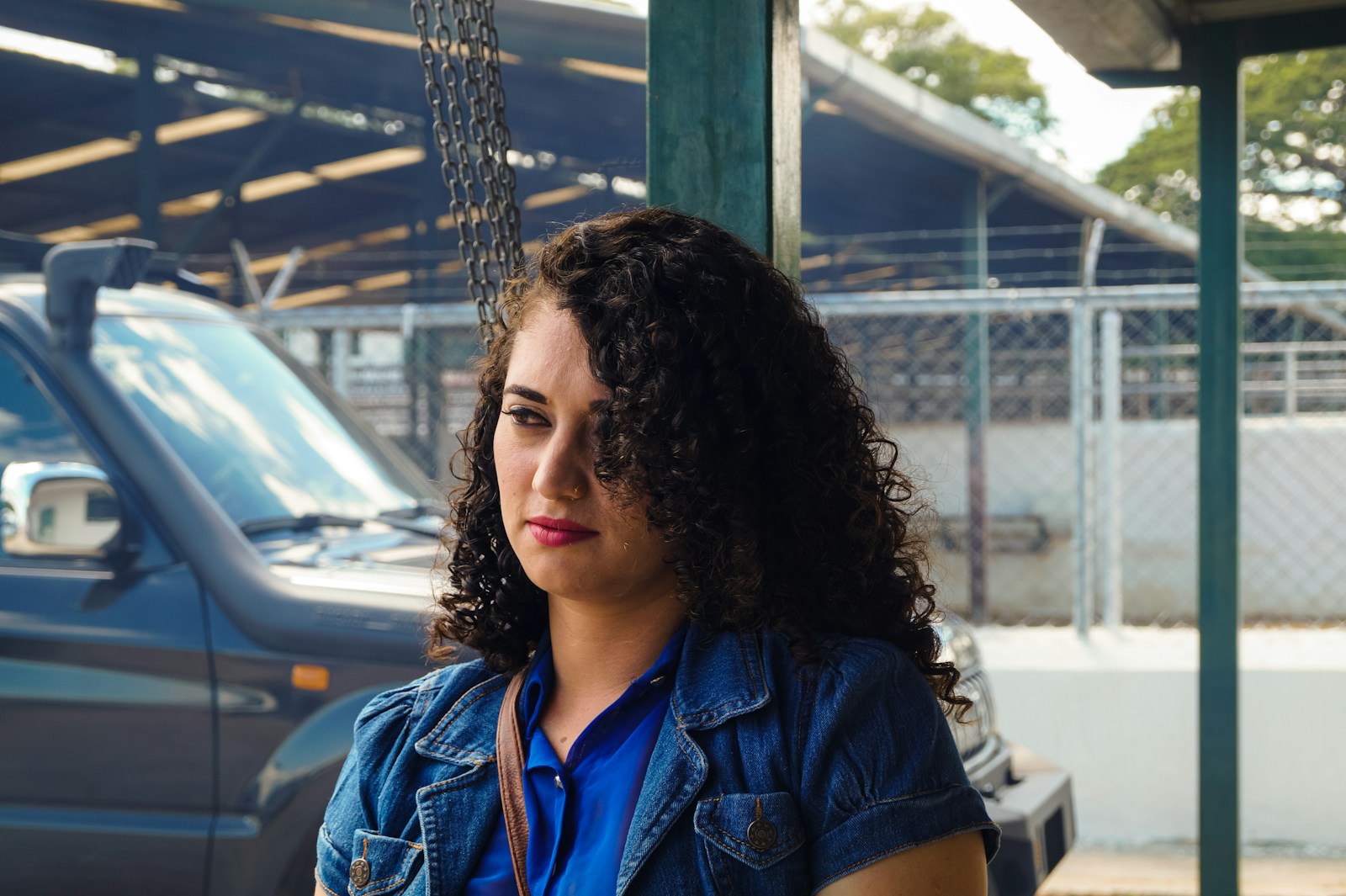 woman in blue denim jacket standing near white car during daytime