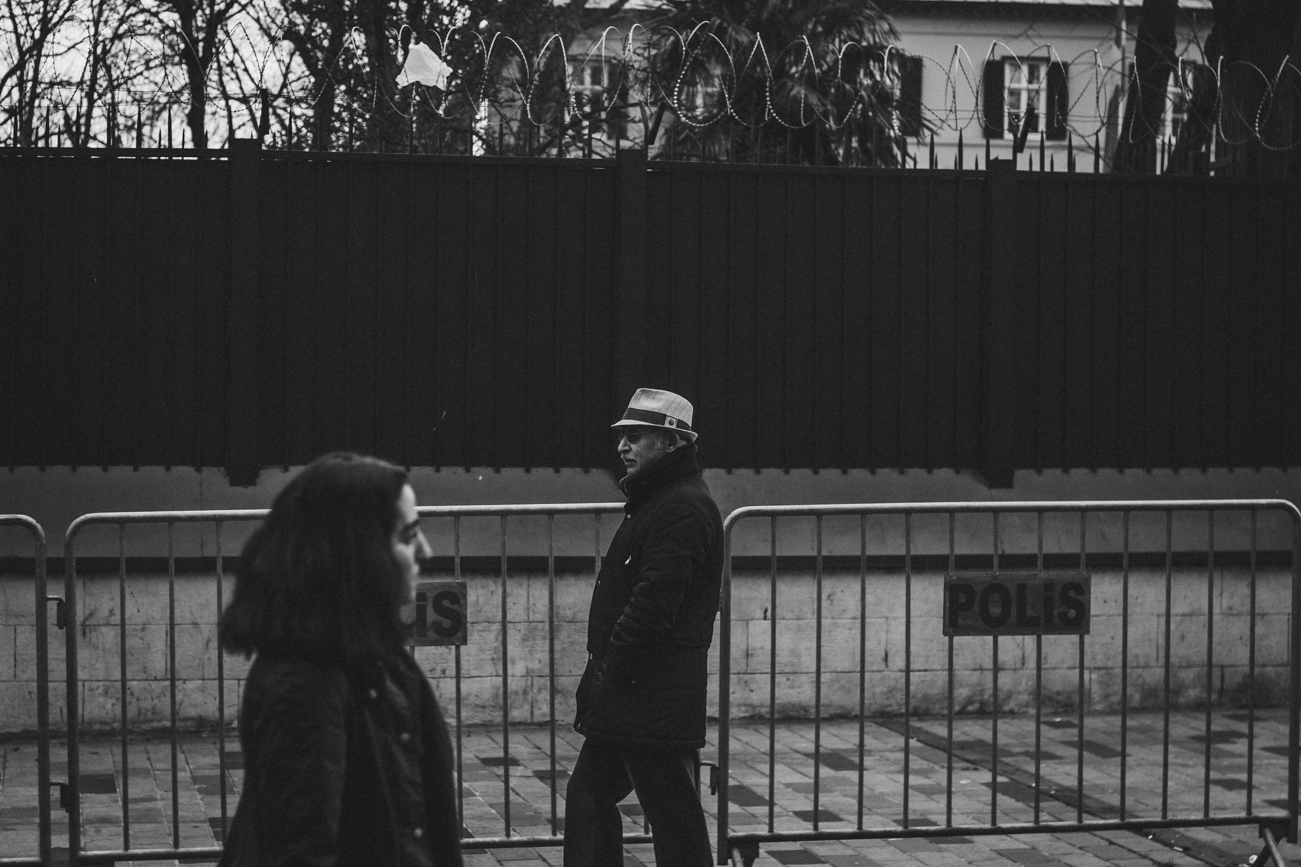 Street photography capturing everyday life near barbed wire fences in Istanbul.