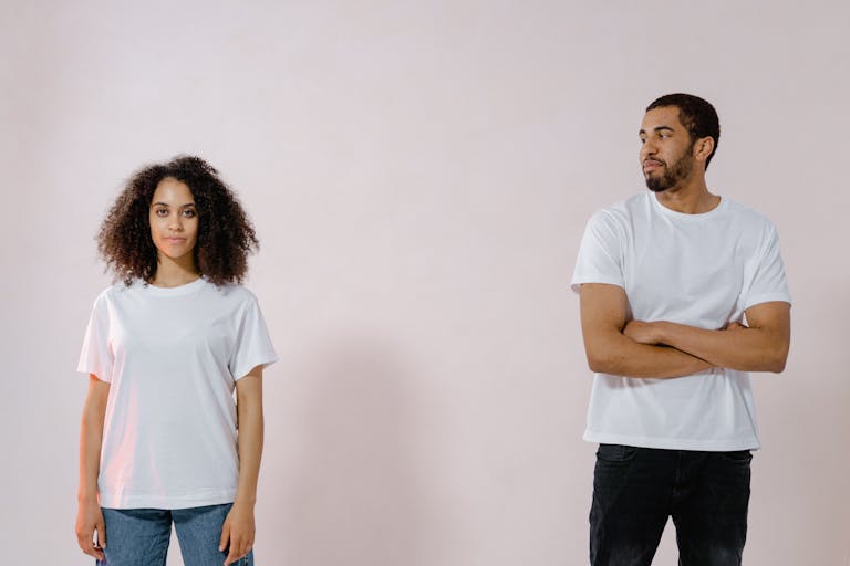 Studio portrait of an African American man and woman in casual white t-shirts looking at each other.