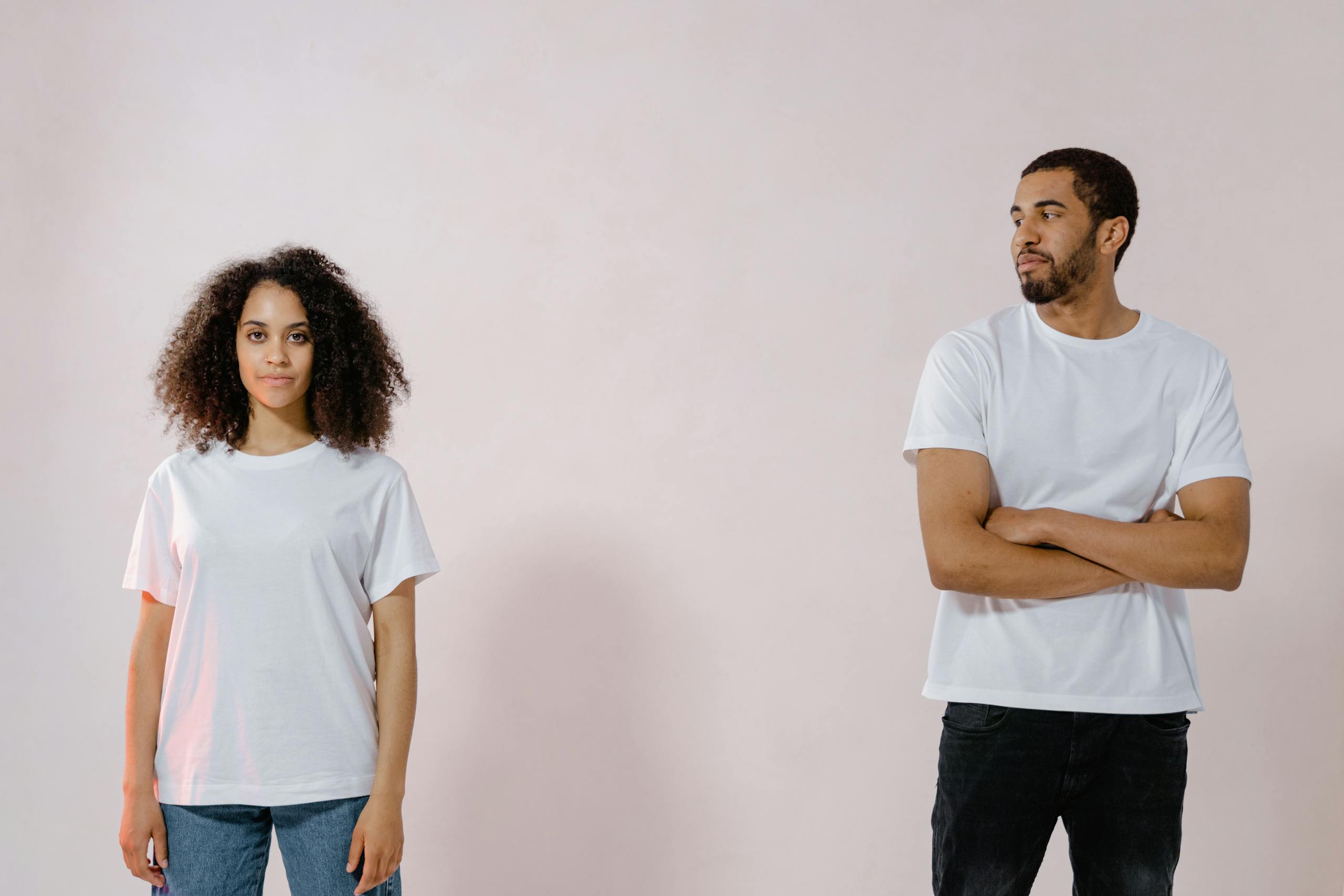 Studio portrait of an African American man and woman in casual white t-shirts looking at each other.