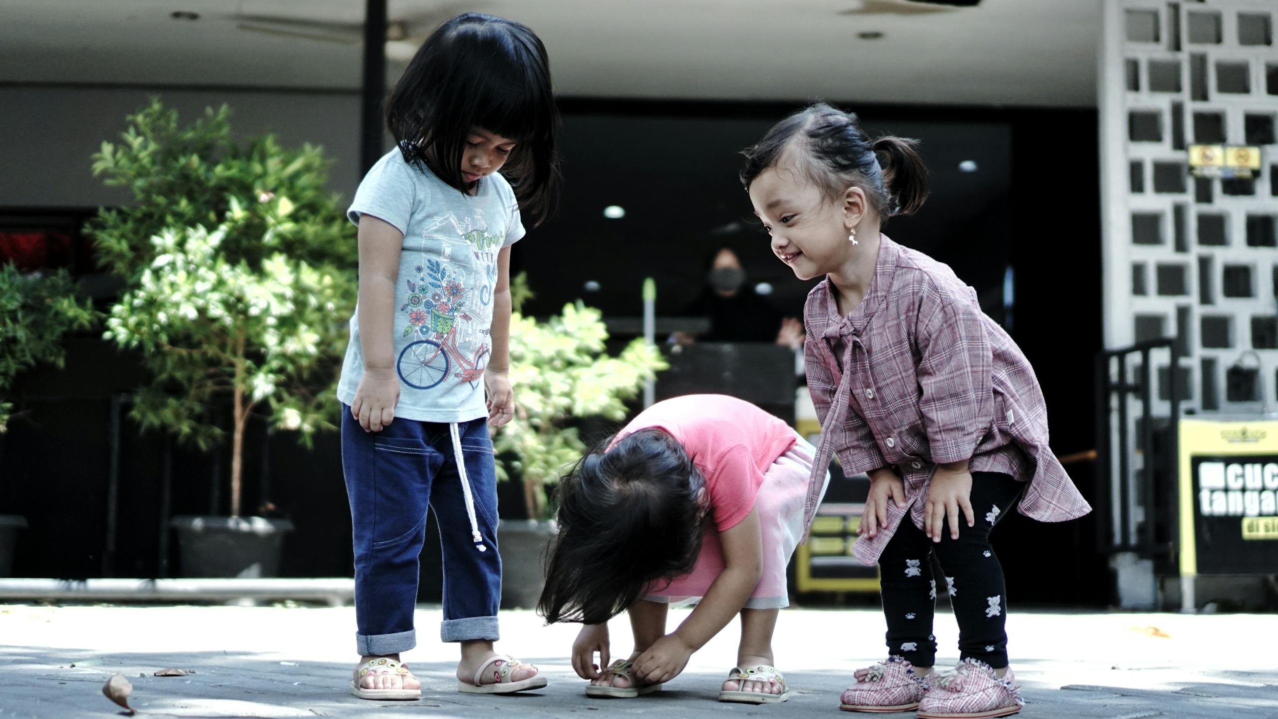 Three Asian girls joyfully playing together outside, capturing a moment of childhood fun.