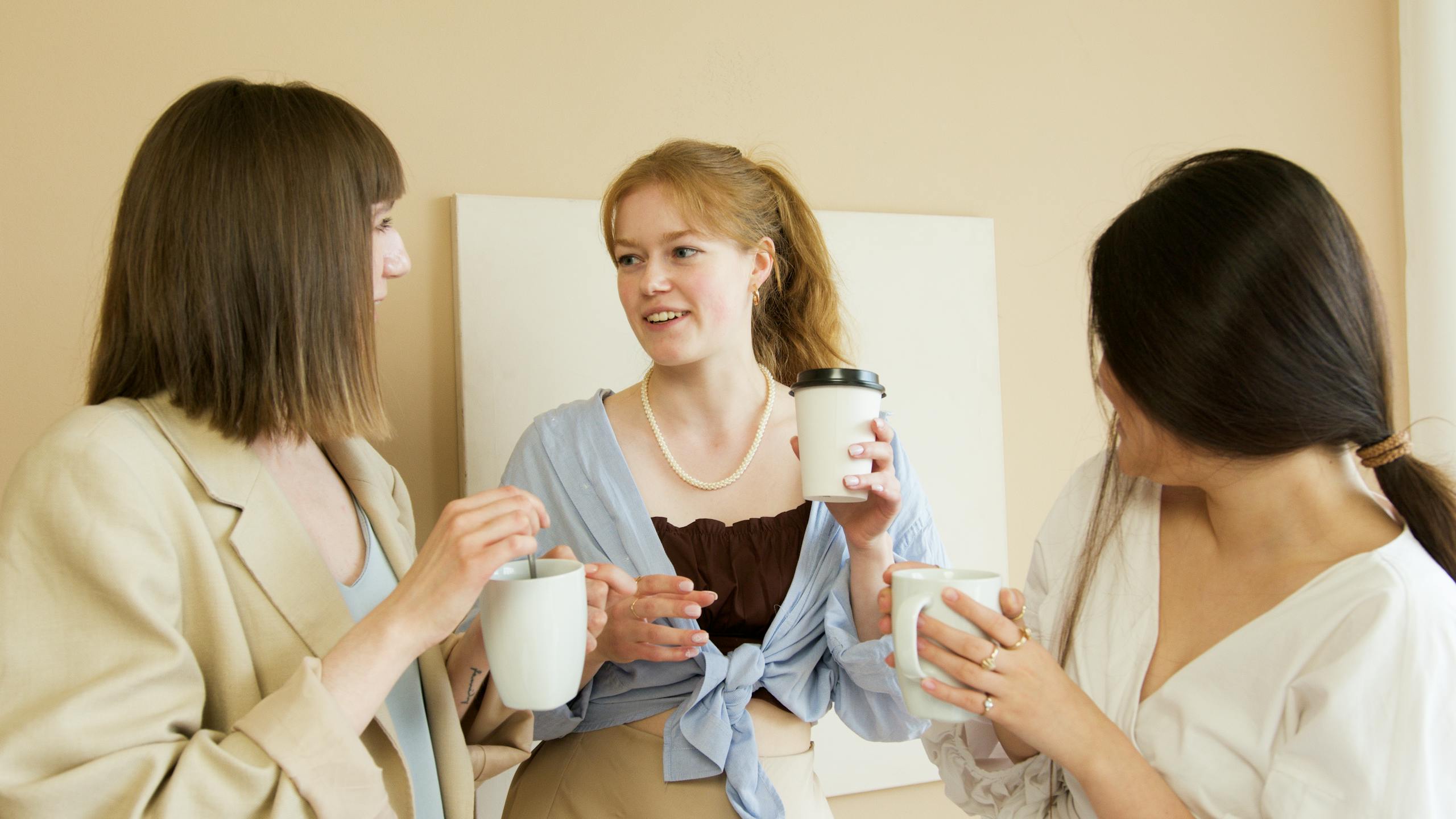 Three women colleagues enjoying a coffee break, chatting and bonding in the office.