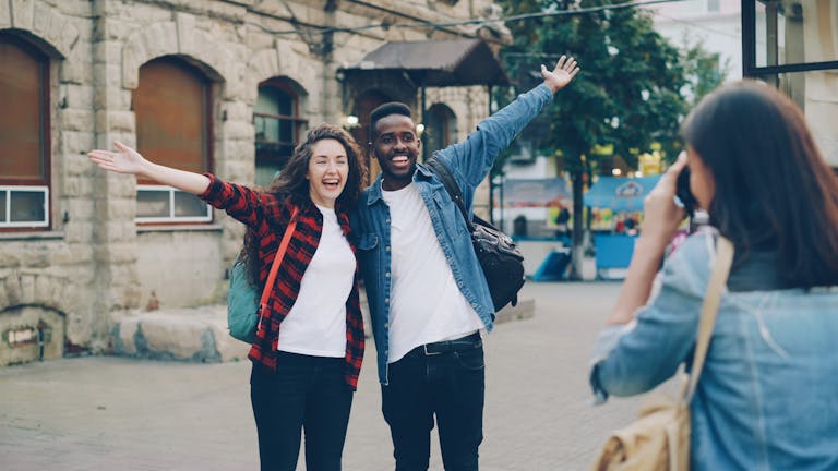 Two cheerful travelers posing for a photo in a city street, capturing joyful memories.