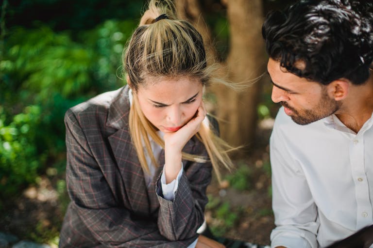 Two colleagues engaged in an outdoor conversation amidst greenery.