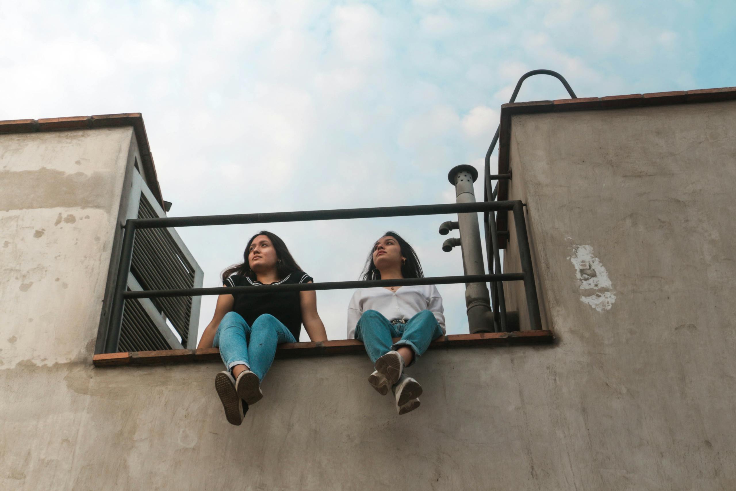 Two friends sitting on rooftop edge in Lima enjoying the view on a clear day.