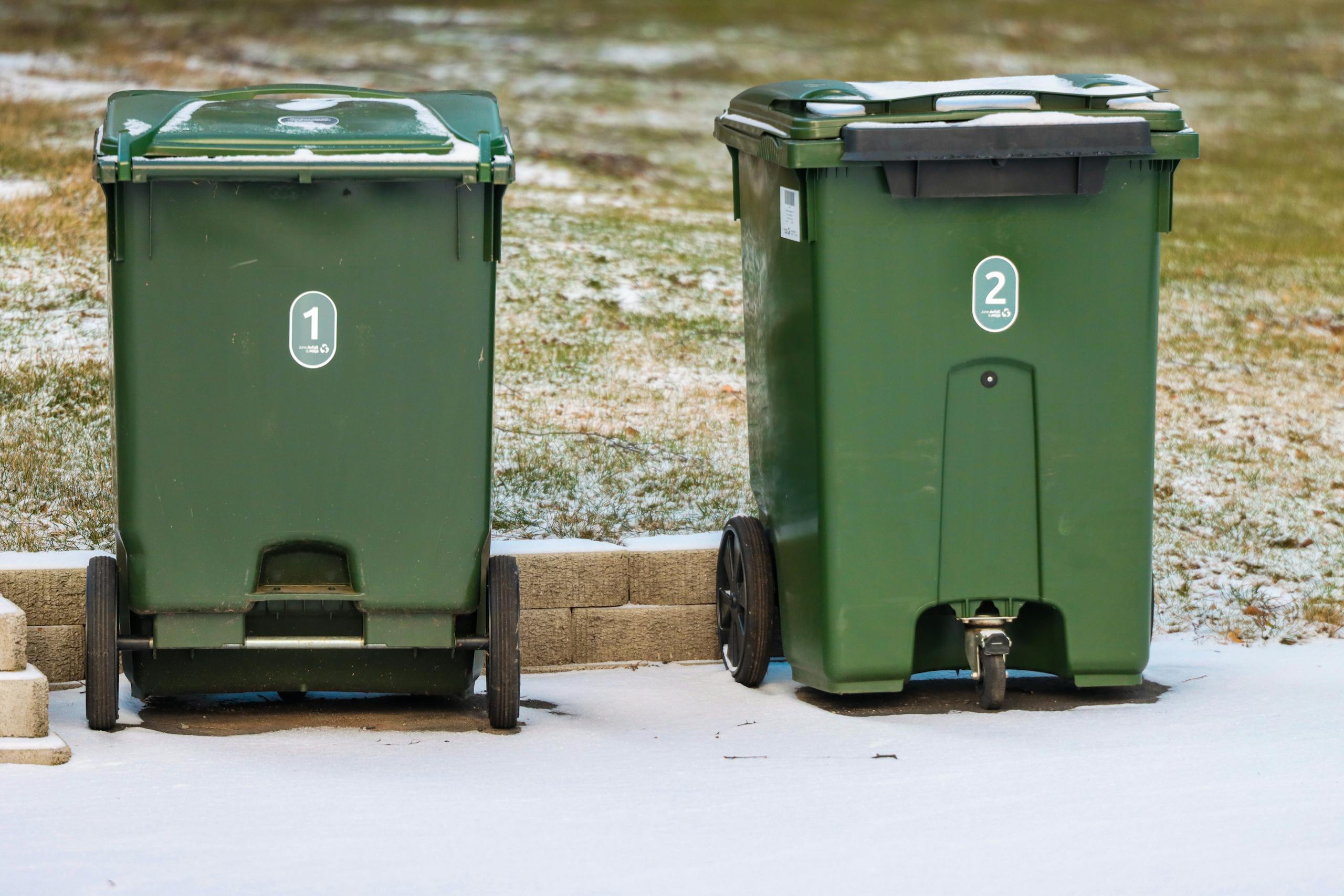 Two green garbage bins on a snowy day in Jönköping, Sweden.
