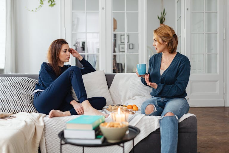 Two women having a heartfelt conversation in a modern living room setting.