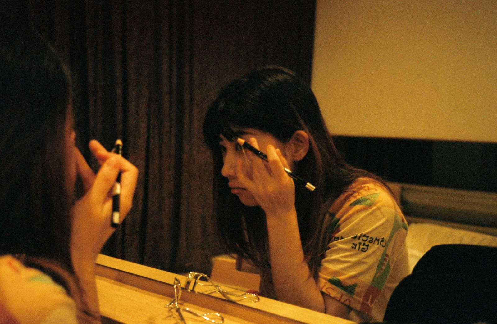 Woman applying makeup in front of a mirror.