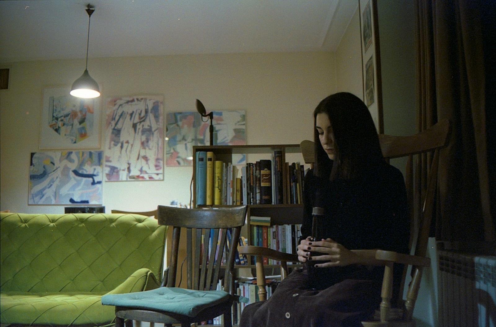 A woman sits in a dimly lit room.
