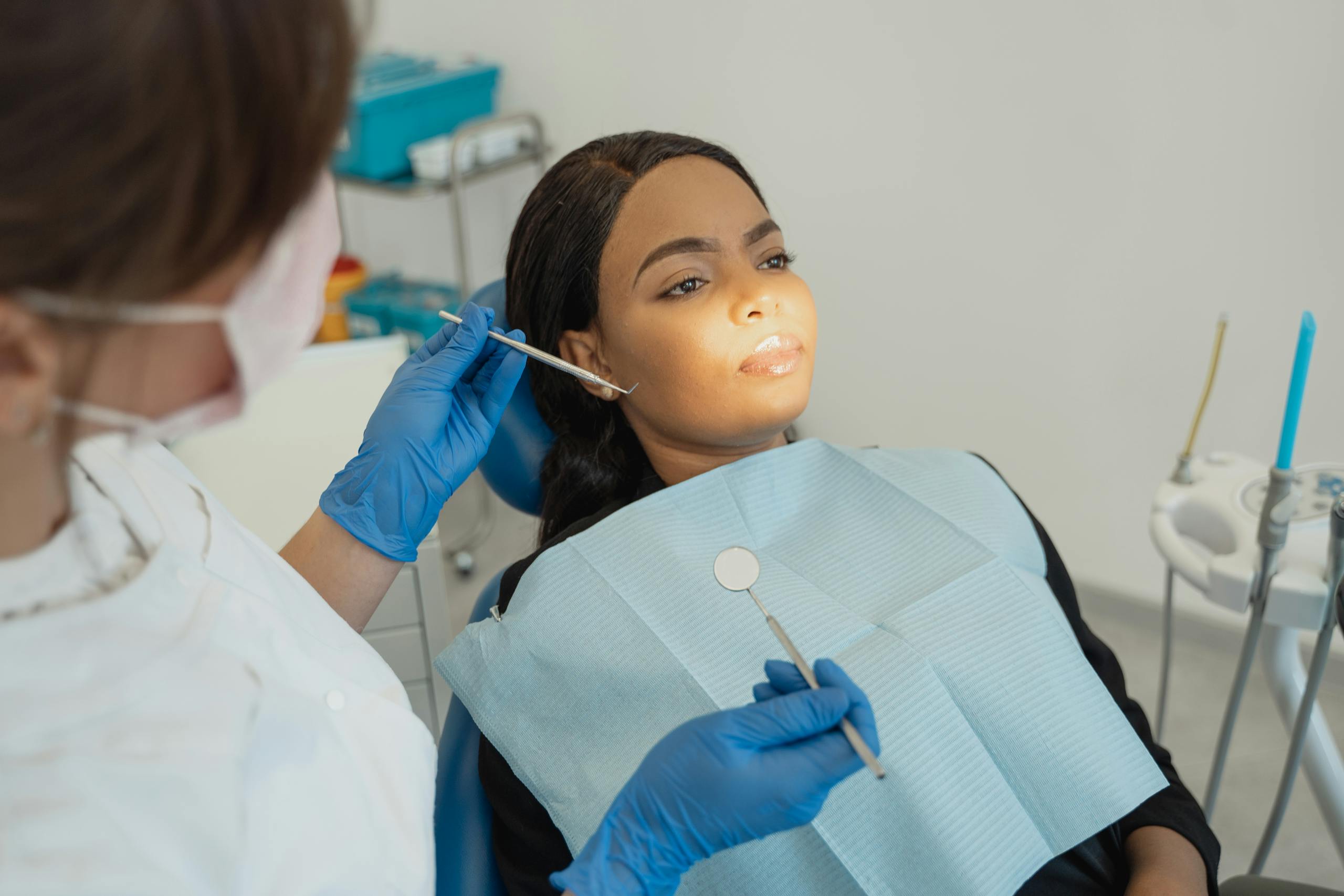 Woman receives routine dental checkup with dentist using tools in modern clinic.