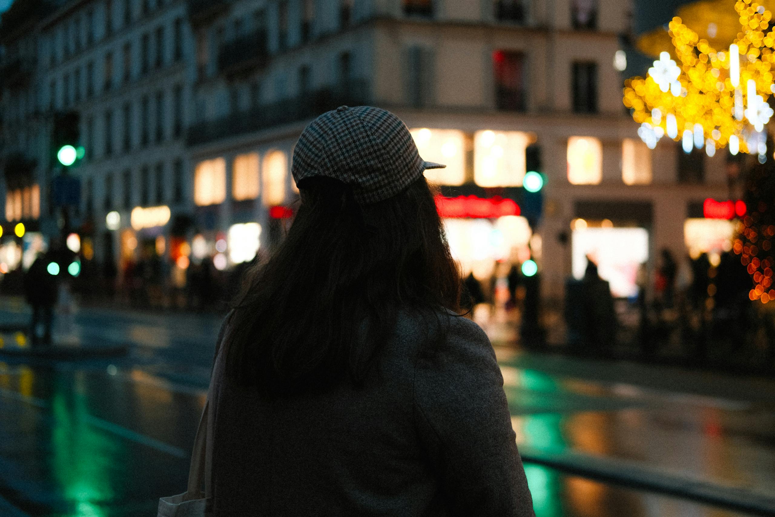 Woman standing at night in a city with illuminated streets, capturing an urban vibe.