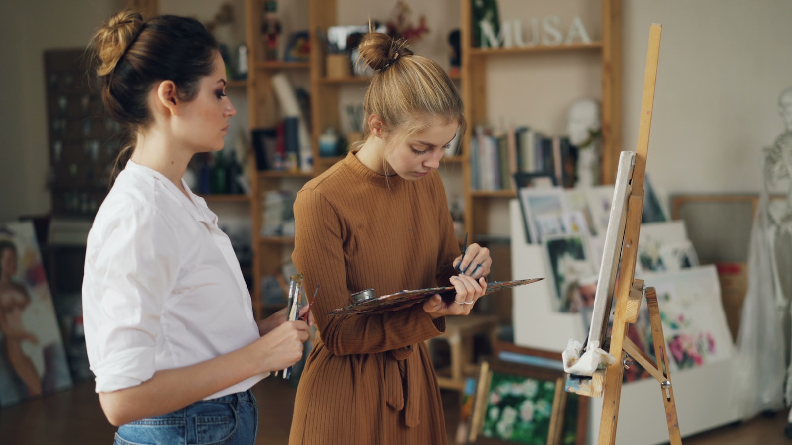 Two women paint in an art studio.