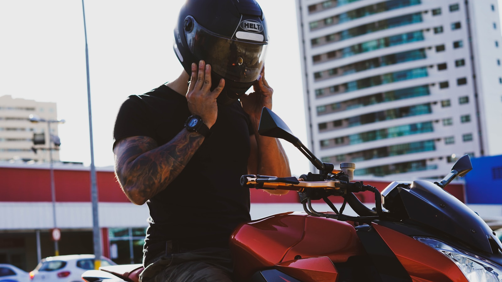 man in black t-shirt and helmet riding red motorcycle