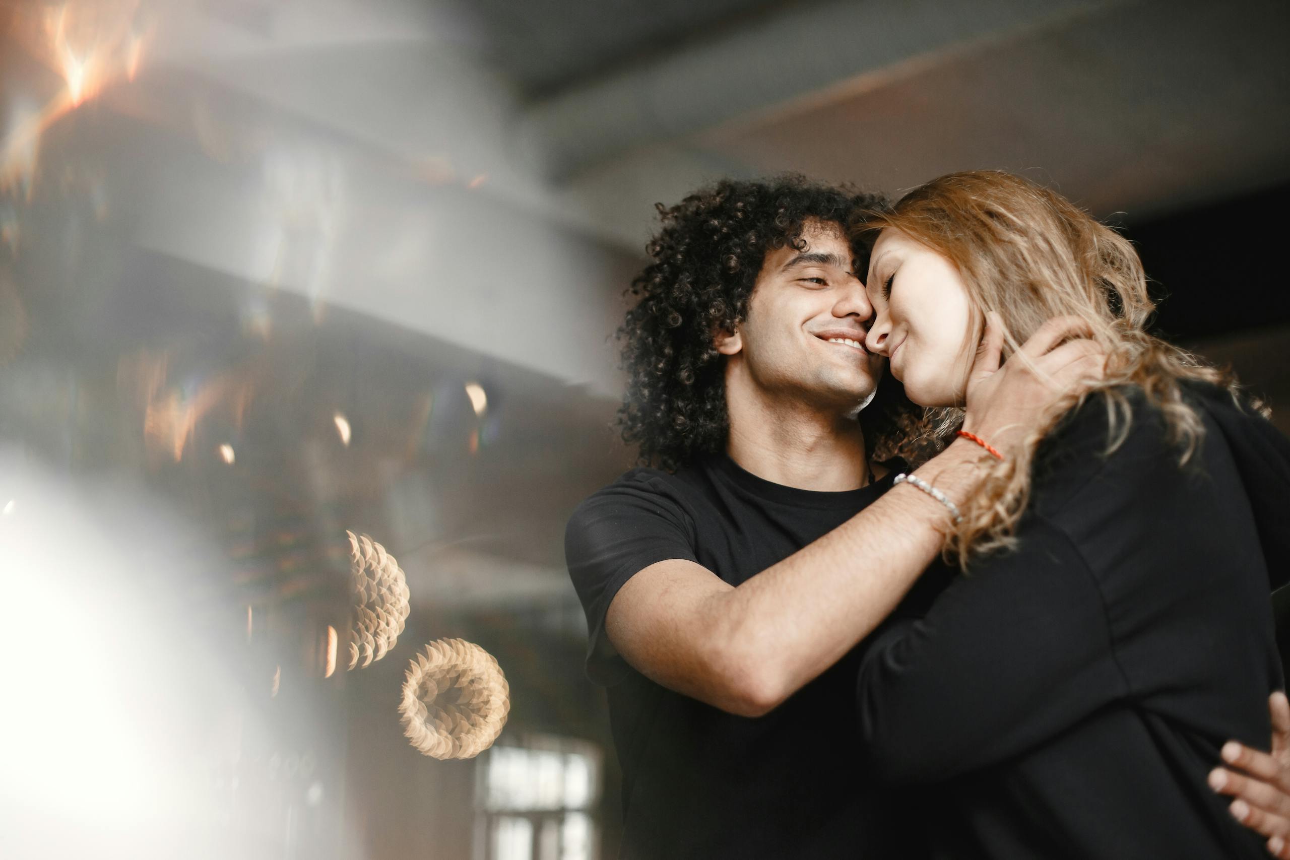 Young couple embracing affectionately indoors, exuding warmth and romance.