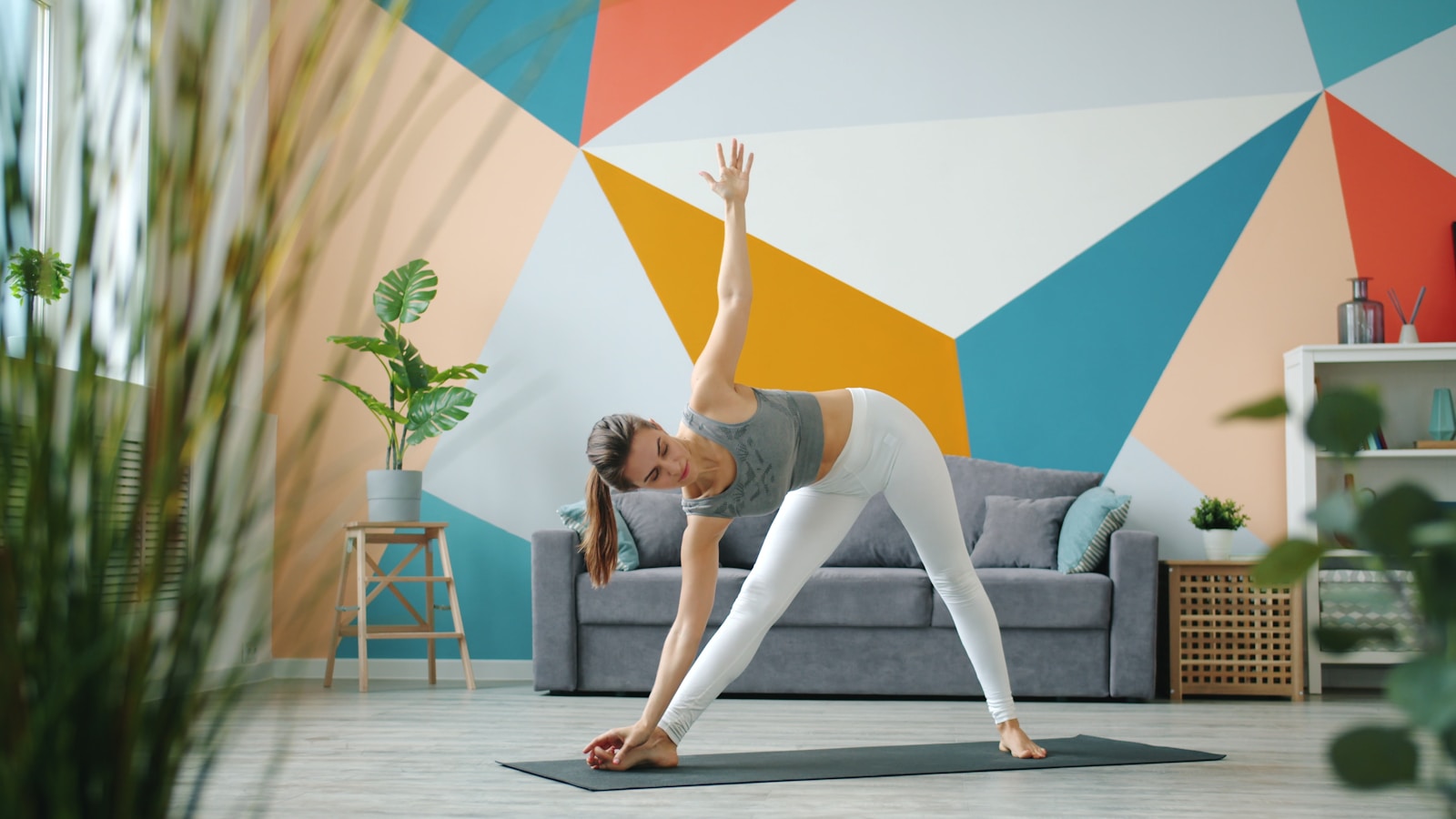 Woman practicing triangle pose yoga at home.