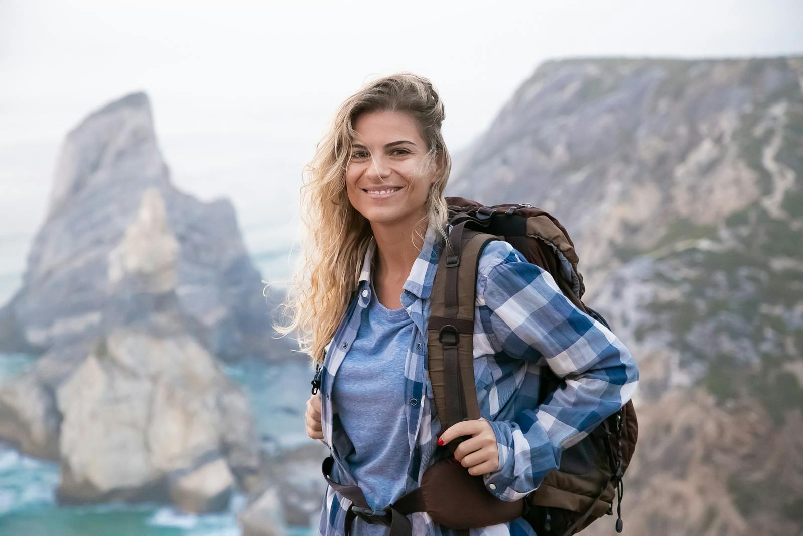 Woman hiking with a backpack on Portuguese cliffs, enjoying the scenic view and fresh air.