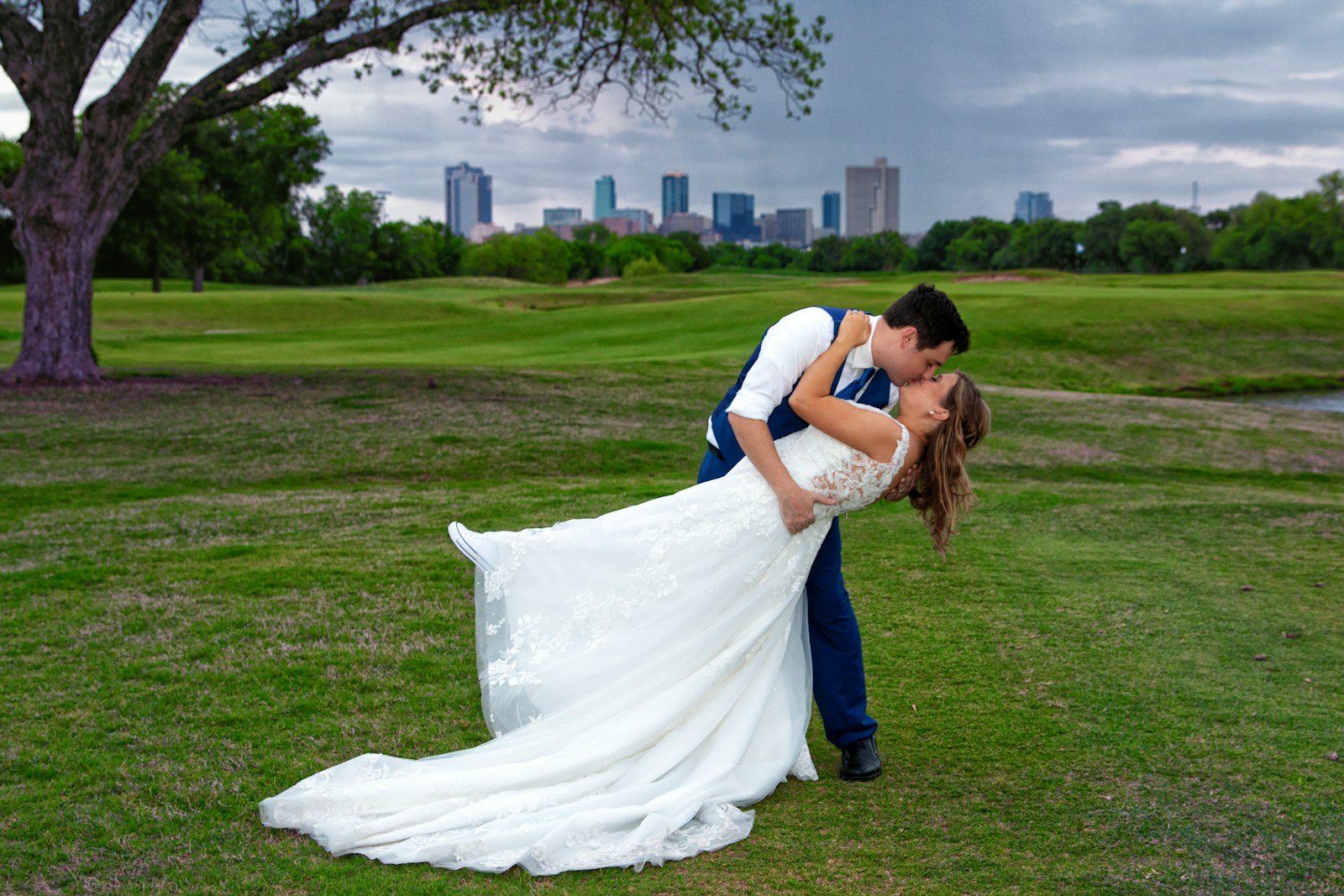 Bride and groom kissing on a grassy field