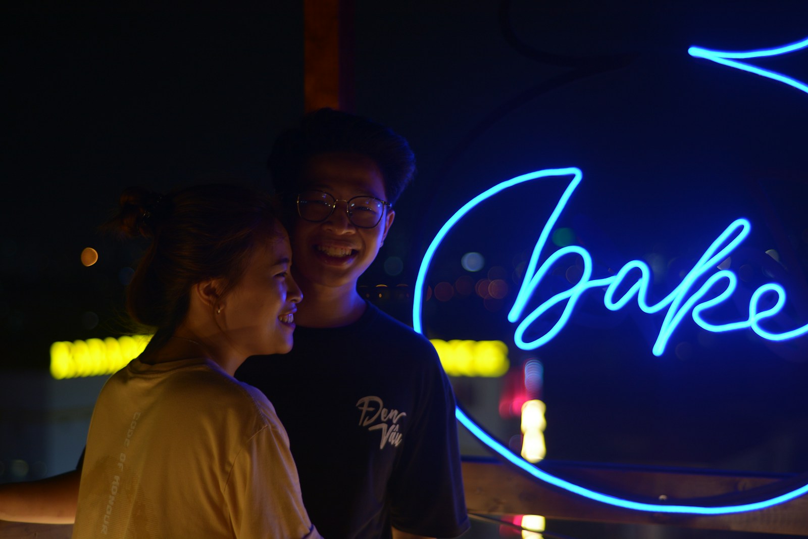 a man and a woman standing in front of a neon sign