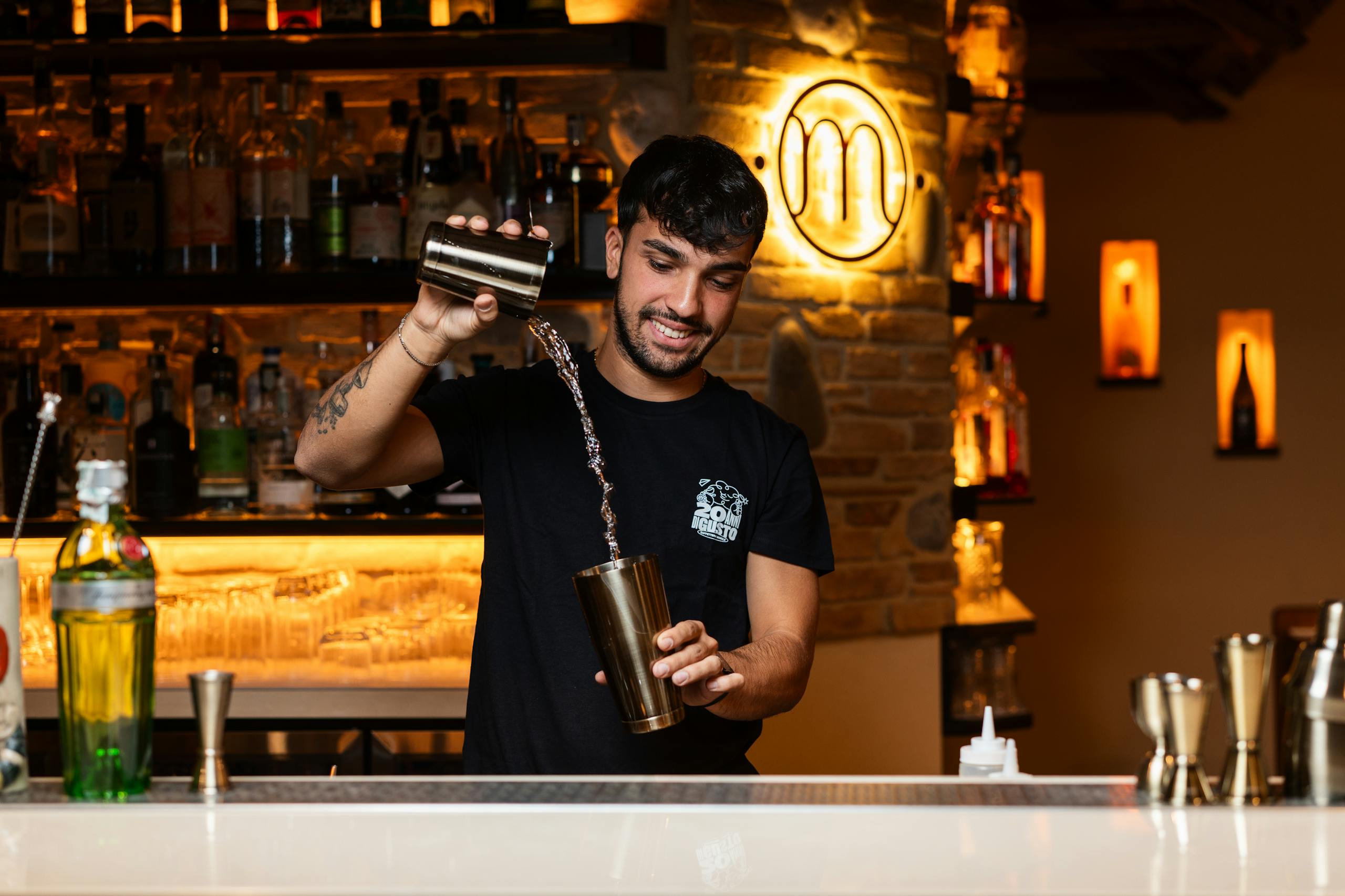 A bartender skillfully pours a cocktail, showcasing mixology techniques in a stylish bar setting.