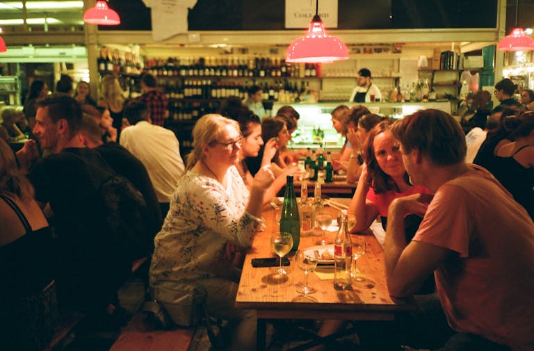 A bustling restaurant scene with people enjoying drinks and conversations on a lively night.