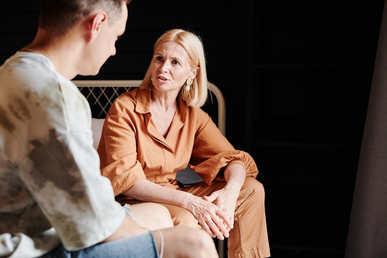A candid moment of a mother and adult son having a heartfelt conversation indoors.