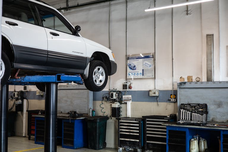 A car is elevated on a lift in a modern automotive repair shop, showcasing tools and equipment.