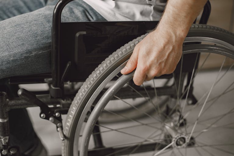 A close-up image showing a hand gripping a wheelchair wheel, portraying mobility and accessibility.