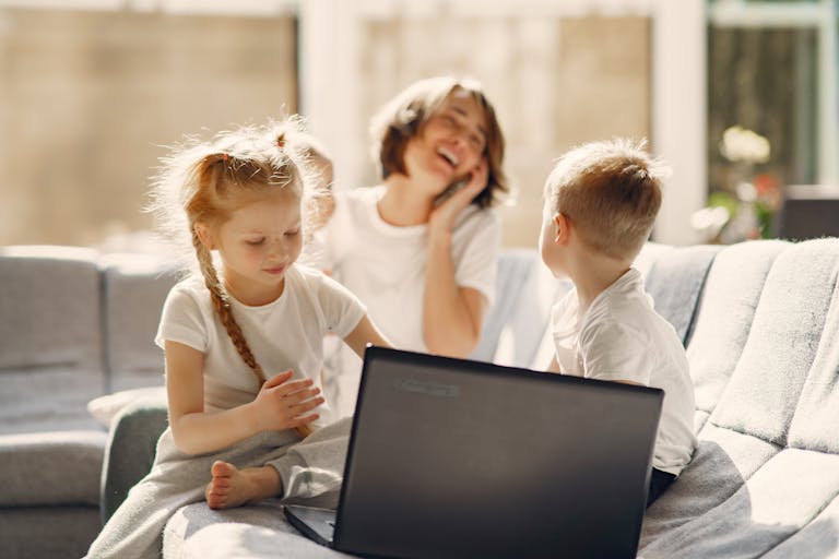 A family enjoying bonding time indoors using a laptop, filled with happiness and togetherness.